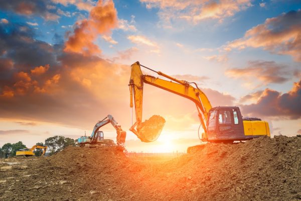 excavator in construction site on sunset sky background